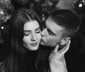 Naklejka premium Young romantic cute couple staing at home and enjoying time together. Lovers hugging in cristmas decorated interior