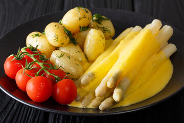 Asparagus with hollandaise sauce, new potatoes, greens and fresh tomatoes close-up. horizontal