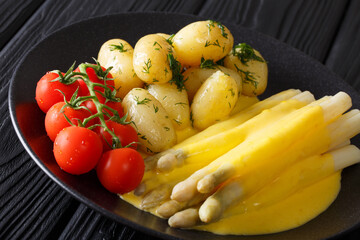 Delicious homemade asparagus with Dutch sauce, fresh potatoes and fresh tomatoes close-up. horizontal