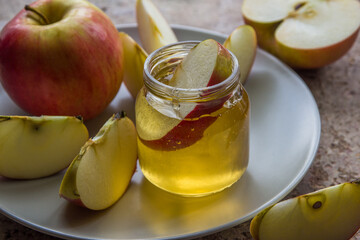 Organic honey in glass jar and red apple on the plate