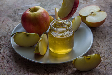Organic honey in glass jar and red apple on the plate