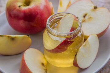 Organic honey in glass jar and red apple on the plate