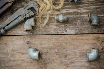 Pipe wrench plumbing fittings on wooden board.