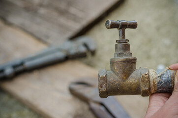 Close up of old valve, pipe wrenches on background