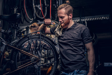 Naklejka na ściany i meble Bicycle mechanic in a workshop with bike parts and wheel on a background.