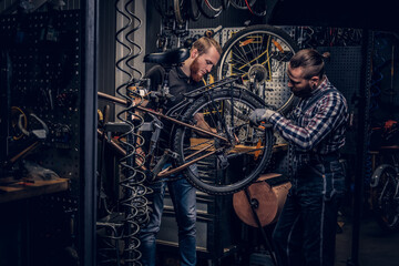 Mechanic fixing rear derailleur from a bicycle. - obrazy, fototapety, plakaty