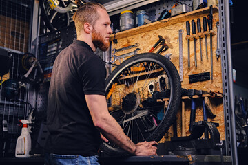 Obraz na płótnie Canvas Bicycle mechanic in a workshop with bike parts and wheel on a background.