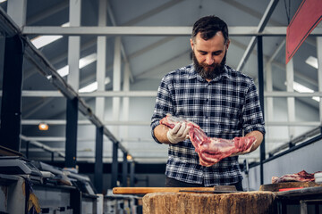 Portrait of a bearded meat man holds fresh cut meat.