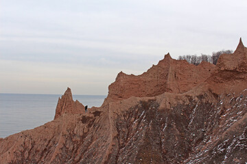 Hiker in the Distance climbing dirt formations next to a Great Lake