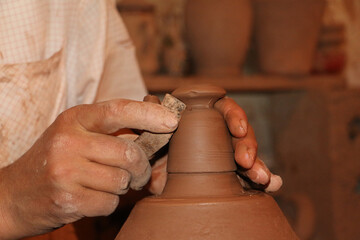Human's hands are creating a clay jar