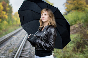 Girl, umbrella and rails in autumn day