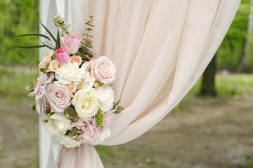 Beautiful wedding arch decorated with beige cloth and flowers