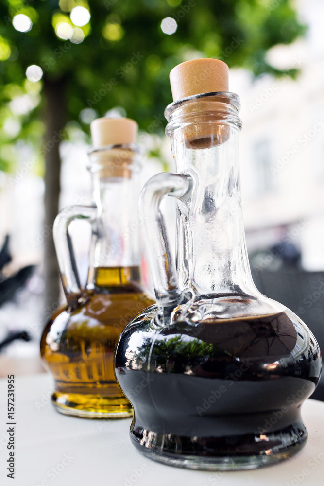 Wall mural bright yellow olive oil and black balsamic vinegar on the restaurant kitchen table. two bottles fore