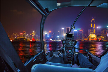 Obraz premium Helicopter cockpit flying on Hong Kong panorama skyline with pilot arm.