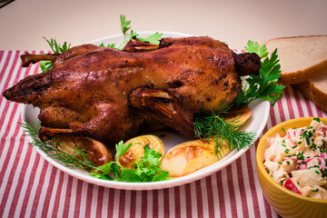 Festive baked duck with apples close-up on a plate on a table.