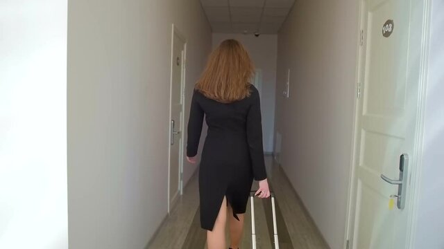 Steadicam slow motion shot of elegant businesswoman pulling suitcase at hotel hall
