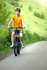 teenager riding a bicycle on the road summer sunlit