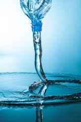Water flow from a plastic bottle on blue background