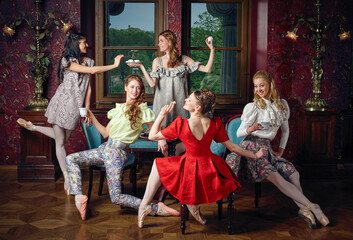 Young caucasian fashion cheerful ballerinas in a pose drinking tea