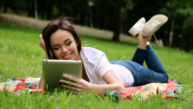 The young beautiful slim dark-haired woman working on the tablet in the spring park. HD