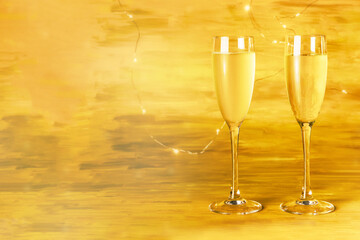Two glasses of champagne on blurred golden background