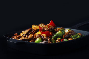 Fried meat and vegetables in cast iron pan