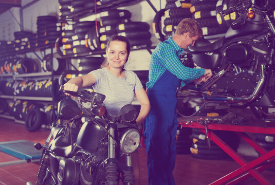 girl with new motorbike in workshop.