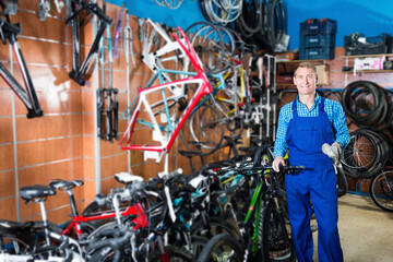 Positive man seller in uniform holding bicycle