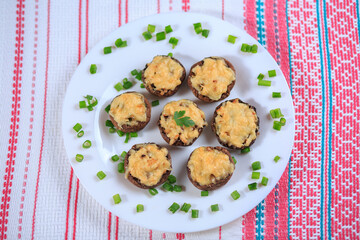 The champignons stuffed with chicken and greens under cheese on a white plate