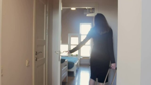 4K video of beautiful young woman with suitcase walking in bedroom