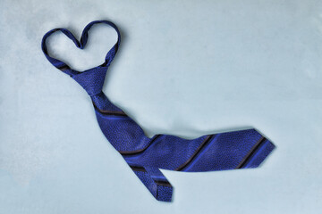 Happy Fathers Day! Classic blue tie on a blue background, heart shape. Conception of congratulation...