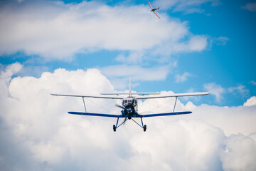 Old military plane flying above white clouds on blue sky