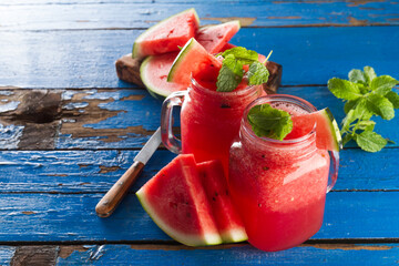Tasty fresh appetizing watermelon drink smoothie with mint on blue table. Closeup.