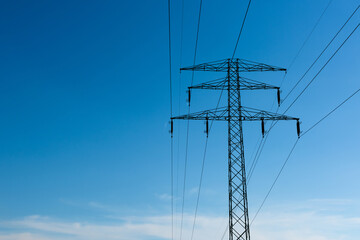 High voltage power lines on pylon at sunny day with blue sky as copy space