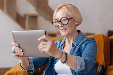 Delighted female holding tablet in both hands
