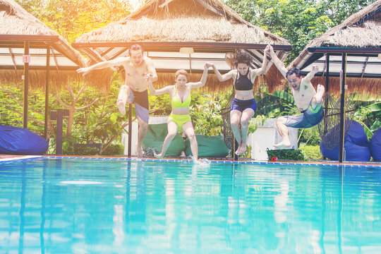 Group Of Friends On Vacation Jumping Into Outdoor Pool