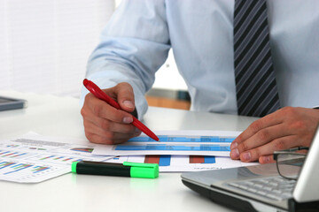 Fototapeta premium Cheerful young businessman sitting at the table with laptop and stretching in the office