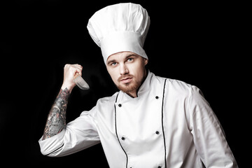 Naklejka premium Young bearded man chef In white uniform holds knife on black background