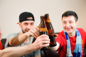 Young men drink beer, eat chips and root for football