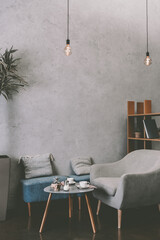 Interior of modern cozy cafe with armchair, table and vintage light bulbs, scandinavian design