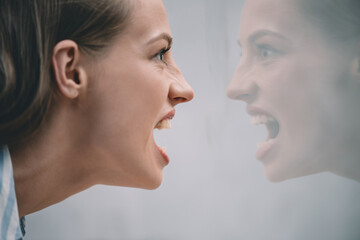 Fototapeta premium aggressive stressed woman screaming at her reflection in mirror