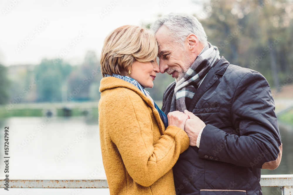 Wall mural Beautiful mature couple standing near lake