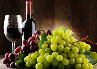 Composition with glass, bottle of red wine and fresh grapes