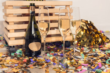 champagne in glasses and bottles with confetti and wooden box