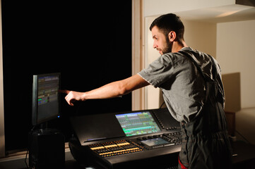A lighting engineer works with lights technicians control on the concert show. Professional light...