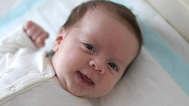 Newborn baby is looking at the camera, smiling (close-up)