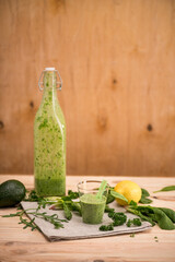 Close-up view of green smoothie in glass and bottle with fresh ingredients