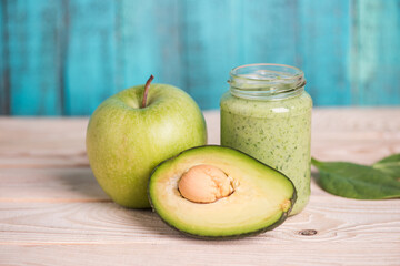 close up of apple with avocado and smoothie in glass jar on wooden table