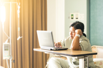 the asia woman in hospital room lying in bed sick and injured using internet in computer laptop feeling concern and serious about her job