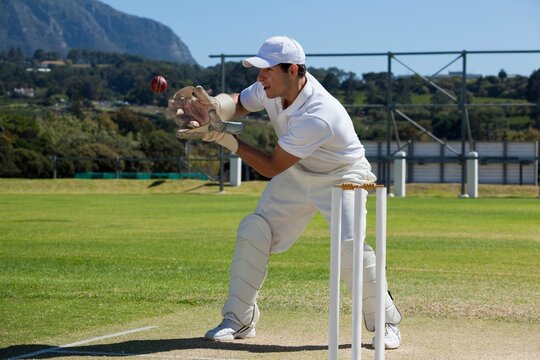 Full length of wicketkeeper catching cricket ball behind stumps